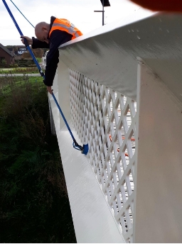 schoonmaker van nellen maakt fietsbrug schoon