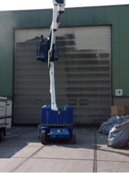 schoonmaker in hoogwerker maakt roldeur schoon